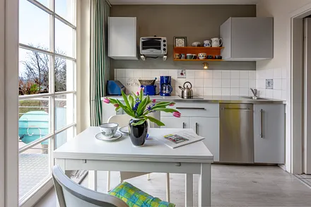 Die Küchenzeile mit Geschirrspüler, Mikrowelle und 2-Platten-Cerankochfeld.