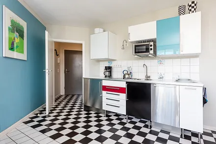 Die Küchenzeile im Wohnzimmer mit Geschirrspüler und Mikrowelle.