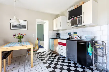 Die Küchenzeile im Wohnzimmer mit Geschirrspüler und Mikrowelle.