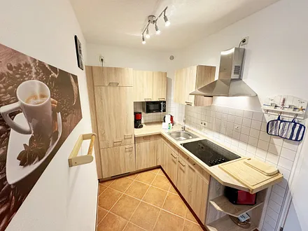 Küchenzeile mit Geschirrspüler, Cerankochfeld, Kühlschrank mit Eisfach, Mikrowelle, Kaffeemaschine, Wasserkocher und ein Toaster