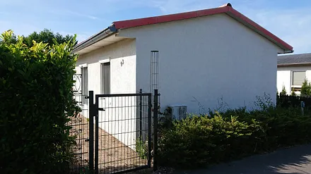 Bungalow mit Einzäunung und recht befindlichem Autoparkplatz