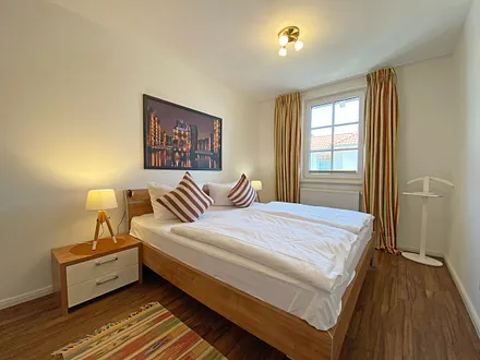 Schlafzimmer mit Doppelbett (1,80 m x 2,00 m), Nachttischablagen und einem großen Kleiderschrank