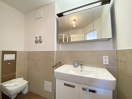 Badezimmer mit ebenerdiger Dusche, Waschtisch, WC, Handtuchtrockner und Fön