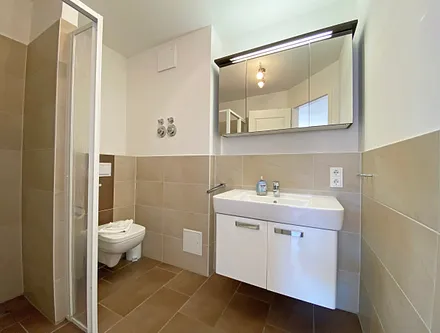 Badezimmer mit ebenerdiger Dusche, Waschtisch, WC, Handtuchtrockner und Fön