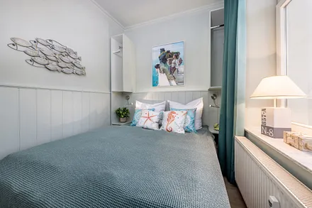 Das kleinere Schlafzimmer mit Doppelbett, kleinem Kleiderschrank und TV.