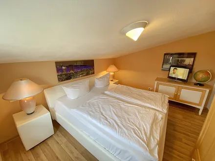 großes Schlafzimmer mit Doppelbett (1,80 m x 2,00 m), Nachttischablagen und Beleuchtung, Kleiderschrank, Sideboard sowie ein TV