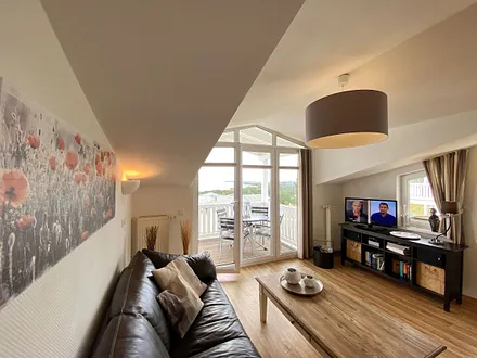 Wohnbereich mit bequemer Ledercouch, Lesesessel mit Hocker, Couchtisch, TV-Board mit Flachbild-TV, Musikanlage und Urlaubslektüre 