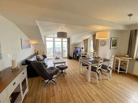 Wohnbereich mit bequemer Ledercouch, Lesesessel mit Hocker, Couchtisch, TV-Board mit Flachbild-TV, Musikanlage und Urlaubslektüre 