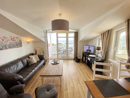 Wohnbereich mit bequemer Ledercouch, Lesesessel mit Hocker, Couchtisch, TV-Board mit Flachbild-TV, Musikanlage und Urlaubslektüre 