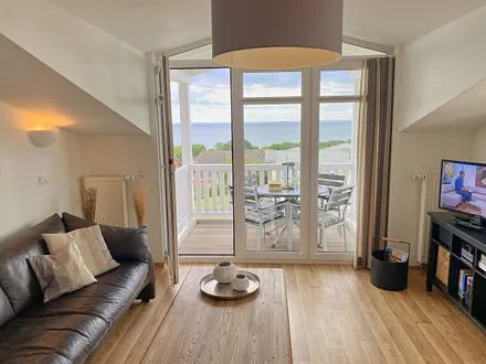 Wohnbereich mit bequemer Ledercouch, Lesesessel mit Hocker, Couchtisch, TV-Board mit Flachbild-TV, Musikanlage und Urlaubslektüre 