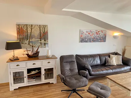 Wohnbereich mit bequemer Ledercouch, Lesesessel mit Hocker, Couchtisch, TV-Board mit Flachbild-TV, Musikanlage und Urlaubslektüre 