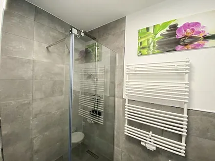 Badezimmer mit ebenerdiger Dusche, Waschtisch mit Spiegel, Handtuchheizkörper, Fön, Kosmetikspiegel, WC und Waschmaschine