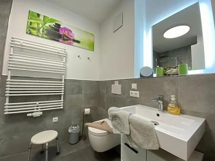 Badezimmer mit ebenerdiger Dusche, Waschtisch mit Spiegel, Handtuchheizkörper, Fön, Kosmetikspiegel, WC und Waschmaschine