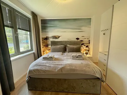 Schlafzimmer mit Boxspringbett ( 1,80 m x 2,00 m) in Komfort-Höhe, Insektenschutzgitter, großer Kleiderschrank, Nachttischablagen mit Beleuchtung, Smart-TV und ein Sideboard