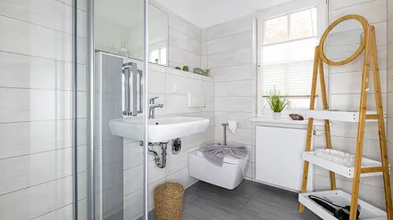 Tageslicht-Bad mit ebenerdiger Dusche, WC, Fön sowie ein Waschplatz mit dazugehörigem Spiegel