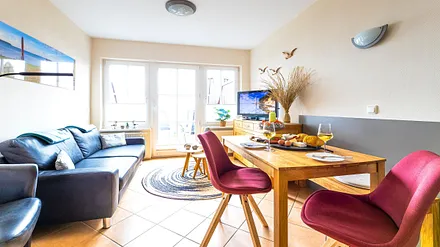 komfortabler Wohnbereich mit Couch, Couchtisch, Sessel, Stehlampe, Kommode mit Flachbild-TV