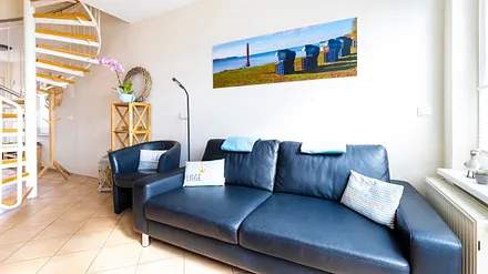 komfortabler Wohnbereich mit Couch, Couchtisch, Sessel, Stehlampe, Kommode mit Flachbild-TV