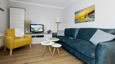 komfortabler Wohnbereich mit Schlafcouch (Aufbettungsmöglichkeit 1,40 m x 1,90 m), Couchtisch, Sessel, Stehlampe sowie eine Kommode mit Flachbild-TV