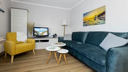 komfortabler Wohnbereich mit Schlafcouch (Aufbettungsmöglichkeit 1,40 m x 1,90 m), Couchtisch, Sessel, Stehlampe sowie eine Kommode mit Flachbild-TV