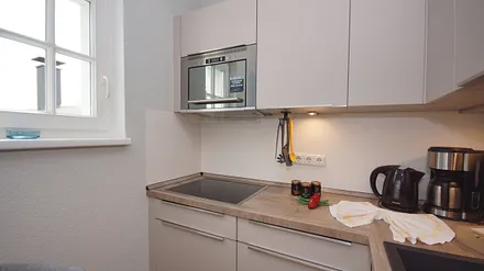 offene und voll ausgestattete Küchenzeile mit Spülmaschine, Kühlschrank mit Eisfach, Dunstabzugshaube, Wasserkocher, Kaffeemaschine, Toaster, Induktionsfeld und Mikrowelle