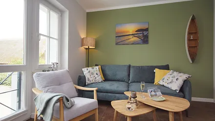 komfortabler Wohnbereich mit einer Couch (Aufbettungsmöglichkeit 1,40m x 1,90m), Couchtisch, Sessel, Stehlampe sowie eine Kommode mit Flachbild-TV 