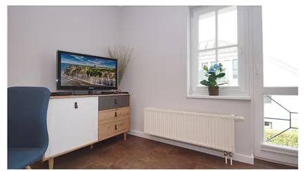 Wohnbereich mit einer Couch (Aufbettungsmöglichkeit 1,40m x 1,90m), Couchtisch, Sessel, Stehlampe sowie eine Kommode mit Flachbild-TV