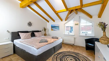 Schlafzimmer mit Boxspringbett (2,00 m x 2,00 m), Nachttischablage, Kleiderschrank, Kommode sowie ein Sessel