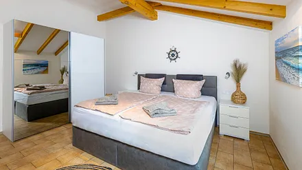 Schlafzimmer mit Boxspringbett (2,00 m x 2,00 m), Nachttischablage, Kleiderschrank, Kommode sowie ein Sessel