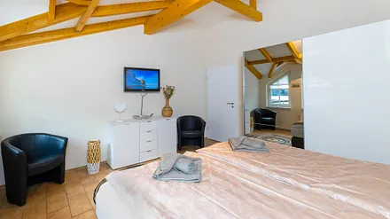 Schlafzimmer mit Boxspringbett (2,00 m x 2,00 m), Nachttischablage, Kleiderschrank, Kommode sowie ein Sessel