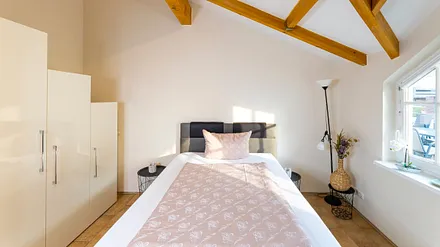 Schlafzimmer mit Boxspringbett (1,40 m x 2,00 m), Nachttischablage, Kleiderschrank, Kommode, Stehlampe sowie ein Standspiegel