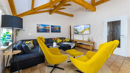 Wohnbereich mit einer Wohnlandschaft (Aufbettungsmöglichkeit für 5./6. Person), Couchtisch, 2 Relaxsessel, 2 Stehlampen, einen Kamin (Holz inklusive) sowie eine TV-Bank mit Flachbild-TV 