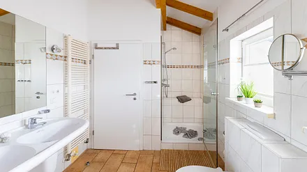 Badezimmer mit geräumiger Eck-Badewanne, WC, Fön, Kosmetikspiegel und ein Doppelwaschplatz mit dazugehörigem Spiegel