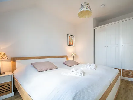 Das erste Schlafzimmer mit Doppelbett und Kleiderschrank