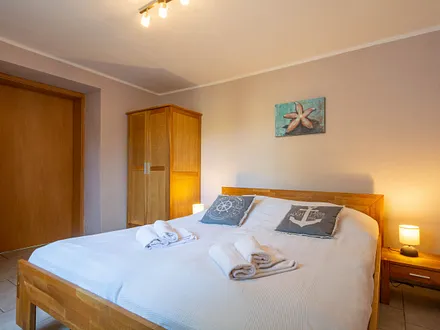 Das erste Schlafzimmer mit Doppelbett und Kleiderschrank