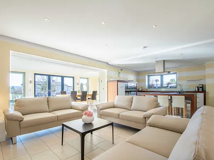 Das helle offene  Wohnzimmer mit Sitzecke und Wintergarten mit einem großen Esstisch