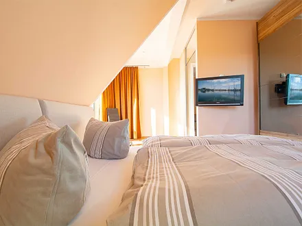 Das erste Schlafzimmer mit Doppelbett und Flachbild-TV