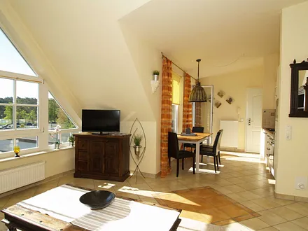 Der Wohnbereich mit Sitzecke und Flachbild-TV, Essecke und Zugang zum möblierten Balkon