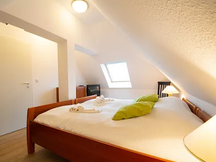 Das zweite Schlafzimmer mit Doppelbett , Kommode und TV in der oberen Etage