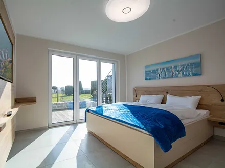 Das erste Schlafzimmer mit Doppelbett und Flachbild-TV