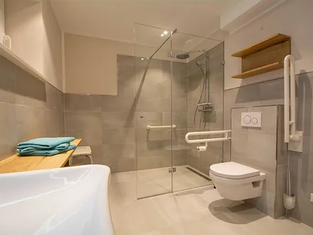 Das erste großzügige Bad mit Regenwaldusche und Haltegriffen an WC und in der Dusche sowie unterfahrbares Waschbecken