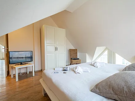 Das erste Schlafzimmer mit Doppelbett, Kleiderschrank und TV