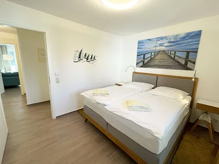 Schlafzimmer mit bequemem Boxspringbett (1,80 m x 2,00 m), Nachttischablagen, geräumiger Kleiderschrank und Verdunkelungsvorhängen