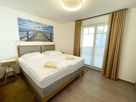 Schlafzimmer mit bequemem Boxspringbett (1,80 m x 2,00 m), Nachttischablagen, geräumiger Kleiderschrank und Verdunkelungsvorhängen