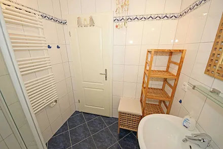 Badezimmer mit flacher Dusche, Waschplatz, WC, Fön, Kosmetikspiegel und Handtuchheizkörper