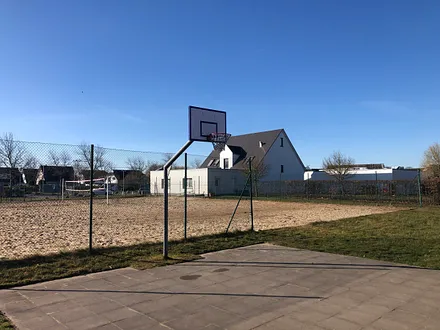 Basketballkorb und Beachvolleyballfeld.