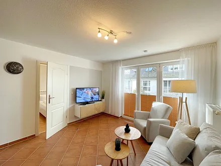 Wohnbereich mit moderner Couch mit Ottomane (1,40 m x 2,00 m), Flachbild-TV, DAB–Radio, DVD-Player, Sessel und Stehlampe