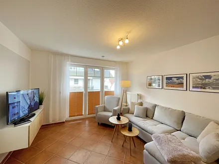 Wohnbereich mit moderner Couch mit Ottomane (1,40 m x 2,00 m), Flachbild-TV, DAB–Radio, DVD-Player, Sessel und Stehlampe