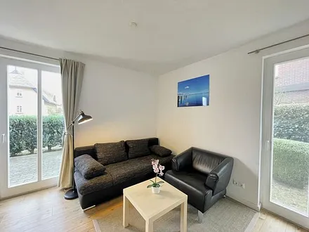 Wohnzimmer mit bequemer Leder-Schlafcouch (Aufbettungsmöglichkeit für 3. Person, 1,00 m x 2,00 m), Couchtisch, Stehlampe, Sideboard, Highboard, Sessel, 55-Zoll-Smart-TV und Bluetooth-Radio 