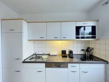 moderne Einbauküche mit Induktionsherd, Kühlschrank mit Gefrierfach, Mikrowelle, Geschirrspüler, Filter-Kaffeemaschine, Nespresso-Kapselmaschine, Wasserkocher, Toaster und Messerblock 
