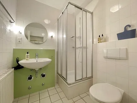 innenliegendes Badezimmer mit Eck-Dusche, Fön, WC, Ablage, beleuchteter Spiegel, Insektenschutzgitter und ein Waschplatz